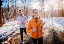 Two people jogging in a snowy forest path
