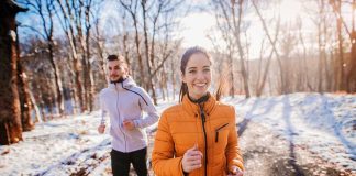 Two people jogging in a snowy forest path