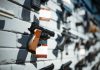 Multiple guns displayed on a wall with price tags