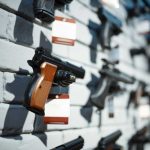 Multiple guns displayed on a wall with price tags