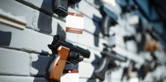 Multiple guns displayed on a wall with price tags