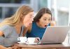 Two women surprised while looking at a laptop.