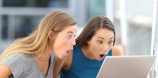 Two women surprised while looking at a laptop.