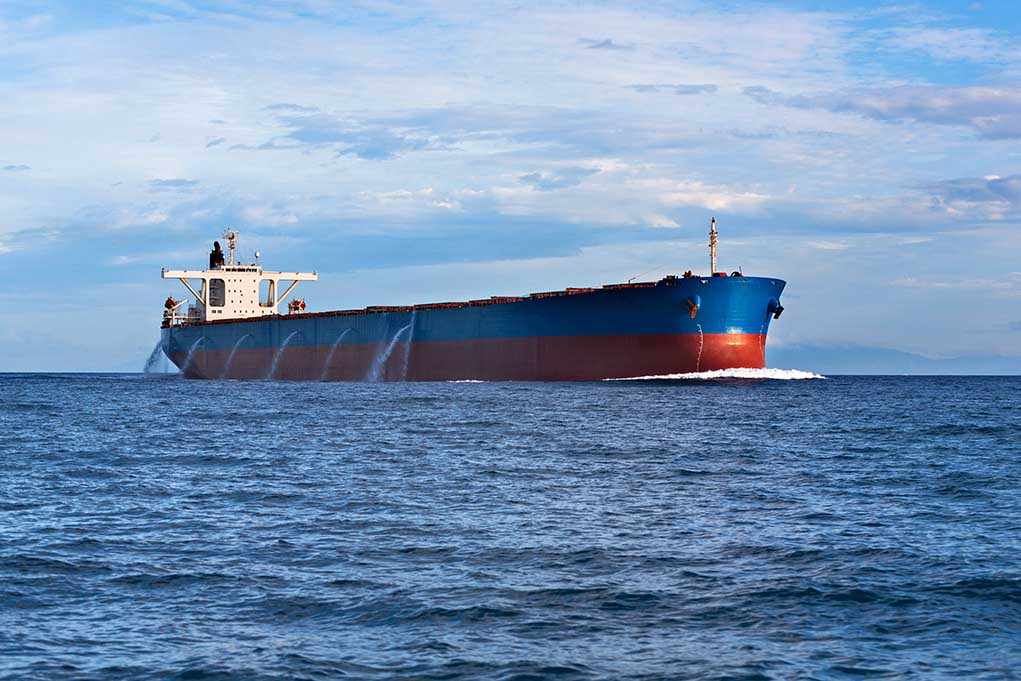 shutterstock_120534520.jpg A large cargo ship sailing on the ocean under a blue sky