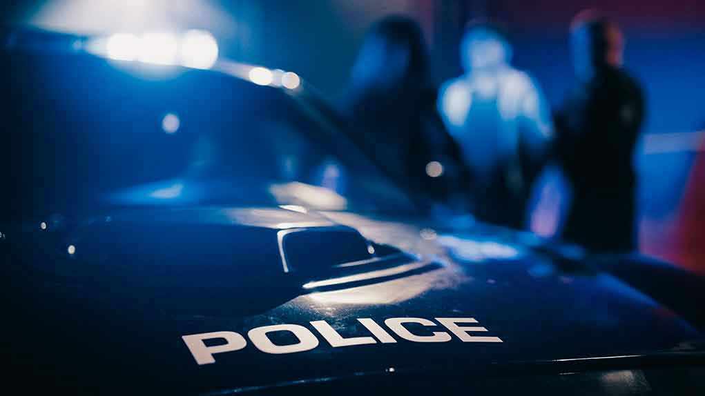2232056701 Police car with blurred figures in the background.
