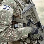 Israel INVADES Hamas – Launches Ground Offensive! Soldier in camouflage gear with Israeli flag patch.