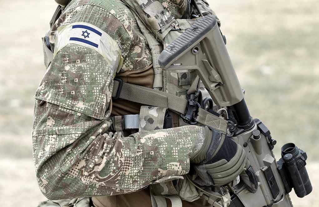 Israel INVADES Hamas – Launches Ground Offensive! Soldier in camouflage gear with Israeli flag patch.
