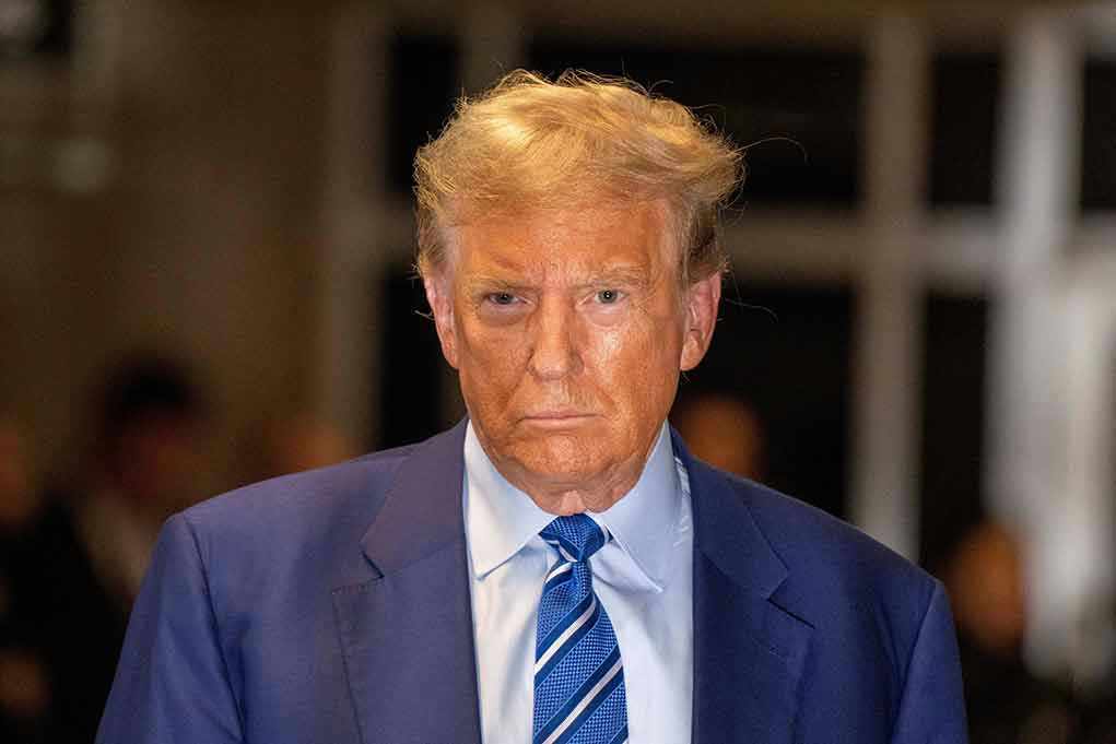 Trump–Epstein Statue SHOCKS DC – Who’s To Blame? Man in blue suit and striped tie, serious expression.