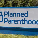 Planned Parenthood CANCELS Abortions – Can No Longer Afford! Planned Parenthood sign on a grassy lawn.