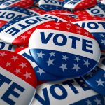 Shock Accusation—Governor STIRS Mid-Terms Controversy! A pile of colorful buttons with the word VOTE and stars, symbolizing election participation