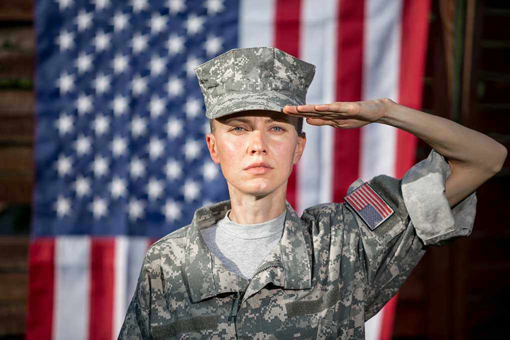 1416735905 Soldier saluting in front of American flag backdrop.