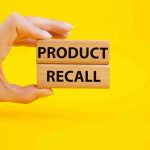 YET Another RECALL — Product PULLED! Hand holding Product Recall blocks on yellow background.