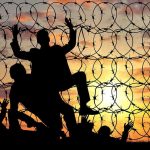 20 Gangsters ESCAPE Prison – Manhunt Underway! Silhouettes of people climbing barbed wire fence.
