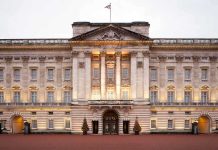 Royal Immunity OBLITERATED—Monarch in Chaos! Front view of Buckingham Palace with illuminated facade and British flag