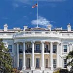 White House Shock: 3 Words Ignite Media Firestorm! The White House with the American flag flying against a blue sky