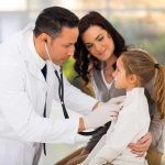 WARNING: Contaminated Cough Syrup KILLS 20 Children! A doctor examines a young girl with a stethoscope while her mother watches