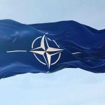 Drone Invasion PANICS NATO—No One Saw This NATO flag waving against blue sky.