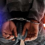 Gang Invasion STOPPED—Federal Agents Strike Hard Person in handcuffs with colorful lights in background.