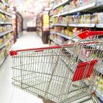 Grocery Giant FLEES Socialist City—What Really Happened? A shopping cart in a grocery store aisle filled with colorful products