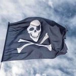 Ocean Heist: Armed Pirates Outsmart Navy A black pirate flag featuring a skull and crossbones waving against a cloudy sky
