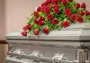 Texas A&M Student’s Mysterious Death Sparks Outrage Silver casket with red rose arrangement on top.