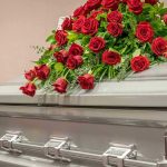 Texas A&M Student’s Mysterious Death Sparks Outrage Silver casket with red rose arrangement on top.