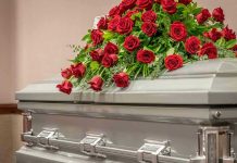 Texas A&M Student’s Mysterious Death Sparks Outrage Silver casket with red rose arrangement on top.