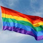 Church UPROAR: Pastor’s Gender Revelation A rainbow flag waving against a blue sky