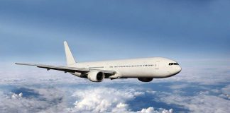 A white airplane flying above fluffy clouds in a blue sky