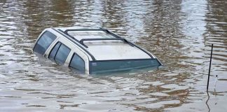 A partially submerged vehicle in floodwaters