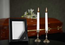 Casket, photo frame, and two lit candles.
