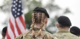 Soldier with braided hair in uniform, American flag visible.