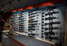 Gun Store CONFESSION Triggers FEDERAL Probe Wall-mounted guns displayed in a store.