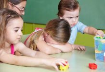 Children at a table with building blocks, one child appears upset