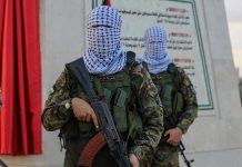 Trump’s Massive Middle East Power Play Masked soldiers holding rifles in front of a monument.