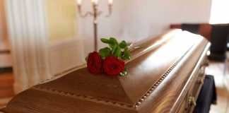 Wooden casket with red roses on top.