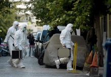Investigators in hazmat suits carrying equipment cases.