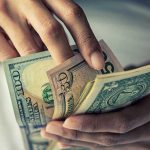 Person holding multiple U.S. dollar bills.