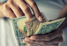 Person holding multiple U.S. dollar bills.