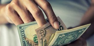 Person holding multiple U.S. dollar bills.