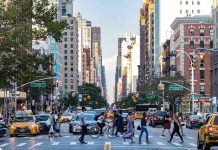 Busy city street with pedestrians, cars, and tall buildings.