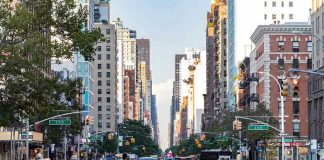 Busy city street with pedestrians, cars, and tall buildings.