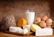 Assorted dairy products including cheese, milk, and eggs on a wooden surface
