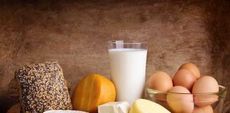 Assorted dairy products including cheese, milk, and eggs on a wooden surface