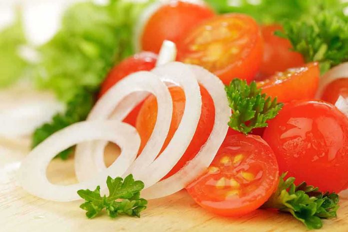 shutterstock_145812959.jpg Close-up of sliced onions, cherry tomatoes, and green herbs on a wooden surface