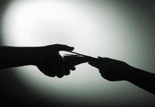 Billionaire-Backed FAKE Protests—$3 BILLION Secret Silhouette of hands exchanging money in dim light.