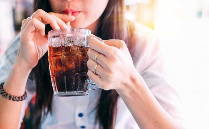 Person drinking soda from a glass mug