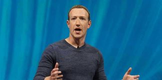 Person speaking on stage with blue background.