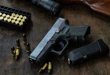 Noise Call Sparks DEADLY Shootout Handgun with ammunition, magazine, and rifle on wooden table.