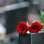Two red roses on a gravestone.